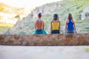 Drei junge Personen sitzen auf einer Steinmauer Drei junge Personen sitzen auf einer Steinmauer